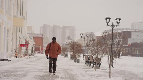 Single Person Journeys Across Snowblanketed City Streets An Isolated Man in Colorful Attire Moves