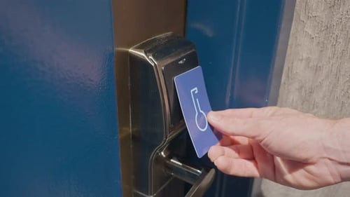 Close up on man's hand using electronic key card to enter hotel suite or room. Person holding RFID c