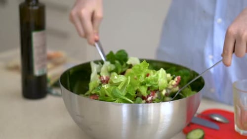 Mixing A Delicious And Healthy Vegetable Salad Using A Big Spoon Into The Stainless Bowl. - close up