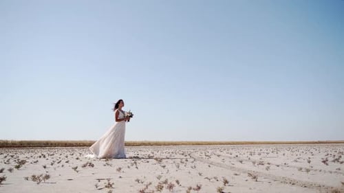 Pretty Young Bride Holding Delicate Bouquet at Desert Landscape Windy Weather Elegance Lady Waiting