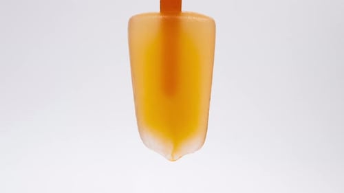 Time lapse of orange juice ice cream melting in hot weather.