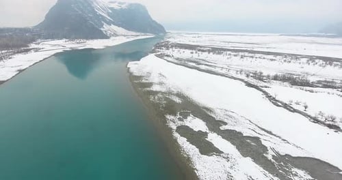 Aerial view of snow-covered mountain, river, and valley in winter, Pakistan.