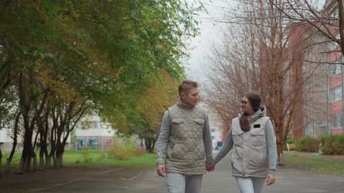 Young Couple Holding Hands During Evening Stroll in Park with Peaceful Background