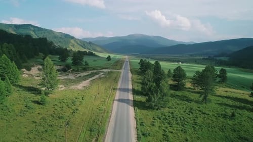 Aerial View of an Asphalt Road in Rural Area Between Green Fields and Hills