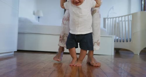 Authentic close up shot of a cute happy little toddler baby boy is taking his first steps with mot