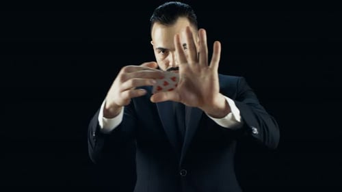 Ein professioneller Zauberer in einem schwarzen Anzug führt den Trick „Verschwinden“ und „Erscheinen“ von Karten aus.