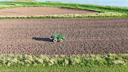 Aerial view of tractor plowing a field at sunset