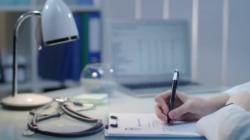 Doctor Writing Prescription at Desk in Medical Office