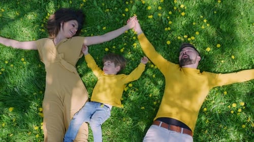 Happy Family Lying on Grassy Field With Flowers