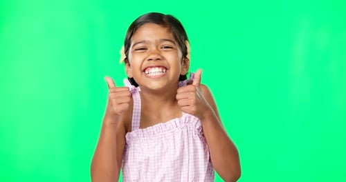 Happy, green screen and face of a child with thumbs up for excitement isolated on a studio