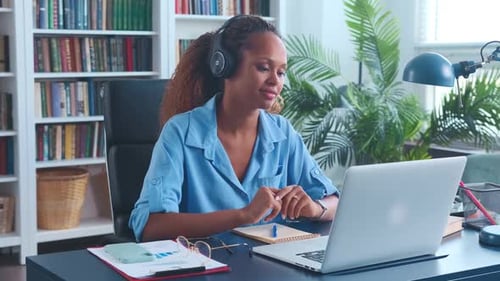 Young African American Woman Looks at Laptop Screen Sits at Office Table