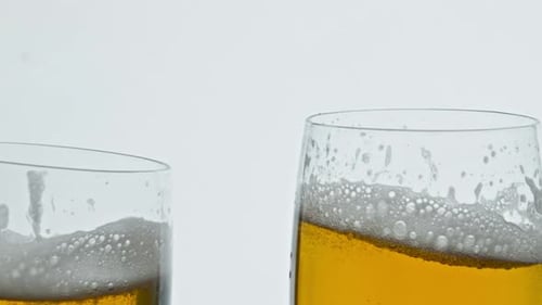 Fondo blanco tintineante de dos vasos de cerveza burbujeante