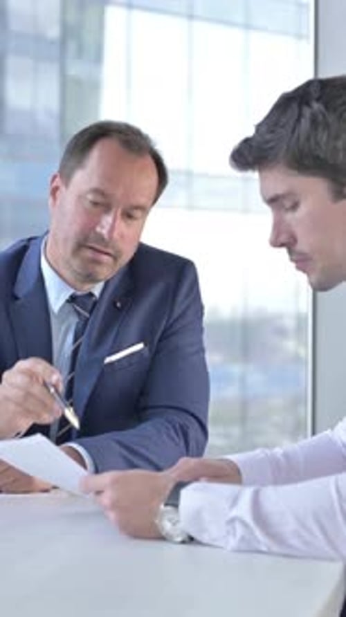 Businessmen Reviewing Documents in Modern Office Meeting