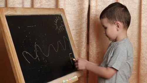 Young Child Drawing on a Blackboard Indoors