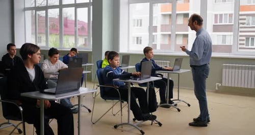 Lehrer spricht im Computerunterricht Vielfältige Schüler lernen im Programmierunterricht Intelligente Kinder