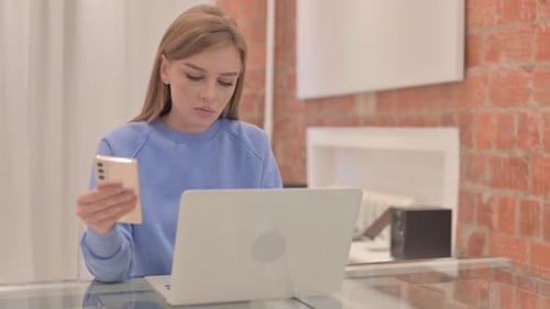 Woman Uses Smartphone and Laptop at Home