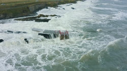 Aerial view of waves crashing against rocks along the coastline during a storm.
Drone Footage.