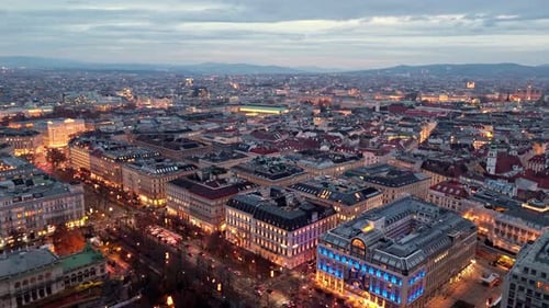 aerial landscape drone shot panning left over Vienna cityscape at night time with illuminated street
