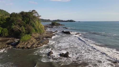 Drone flying over sea waves crashing on rocks on coast of Costa Rica