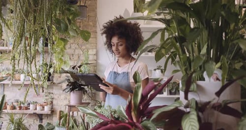 Young adult female small business owner working on digital tablet in store taking inventory