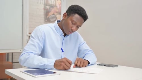 African Businessman Working on Documents in Office