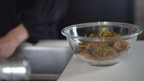 A woman removes seeds from plum fruit taken out from plum syrup