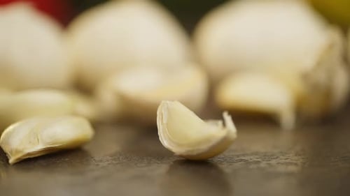 Slow Motion Video of Garlic Spinning on a Table Against Background of Vegetables