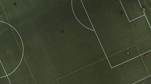 Aerial, top down, drone shot panning above people playing on a soccer field, spring evening, in Pita