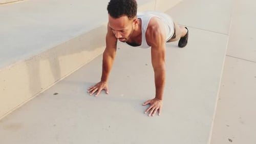Young athlete doing workout, push ups on the embankment