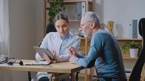 Doctor Explains Tablet to Elderly Male Patient