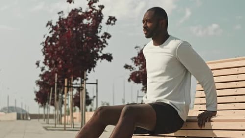 Black Man Doing Triceps Dips by Street Bench Outdoors