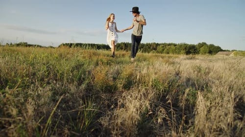 Happy Couple Running in Grassy Field