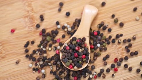 Close Up of Wooden Spoon with Multicolored Peppercorns on Board