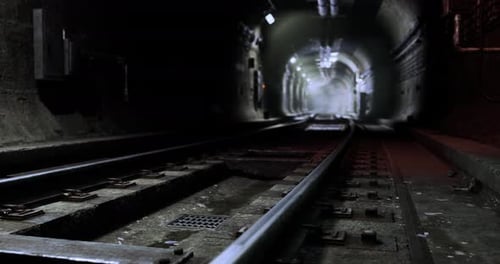 Underground Railway Tracks Lead Into Dark Tunnel with Soft Lighting Ahead