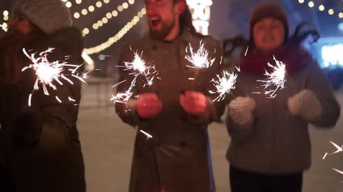 Cheerful Friends Have Fun Partying with Sparklers in Hands at Christmas Market People Jump and Dance