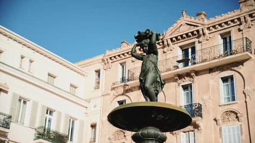 Close up view of a bronze fountain statue with flowing water, surrounded by classic architecture in