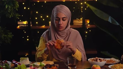 Muslim Woman Enjoying Dinner Amidst Warm Ambiance