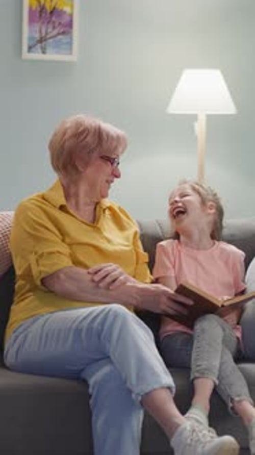 Child and Adult Laughing While Reading a Book