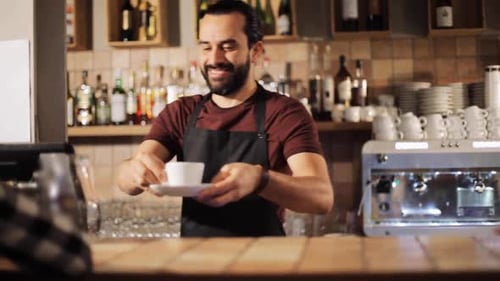 Barista sorridente servindo café para um cliente em sua pequena cafeteria