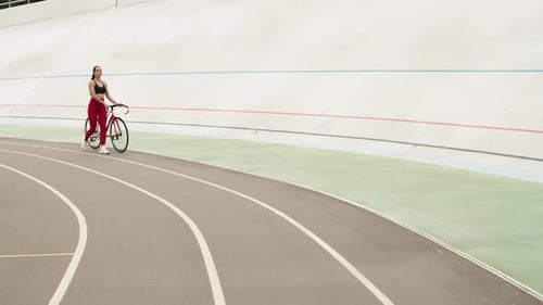 Sexy sporty woman walking with bicycle at outdoor stadium track for fitness