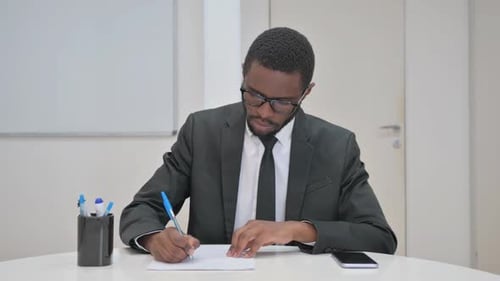 Man in Suit Writing at Desk in Office