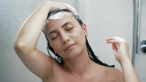 Woman Washing Hair with Shampoo in Shower