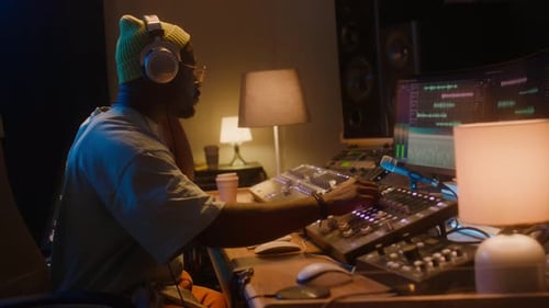 Black Male Sound Engineer Editing Music Track on Workstation Alone in Studio