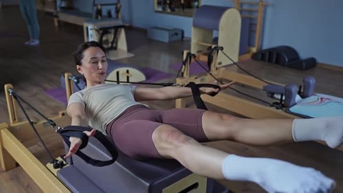 Woman Doing Pilates on Reformer Machine in Studio