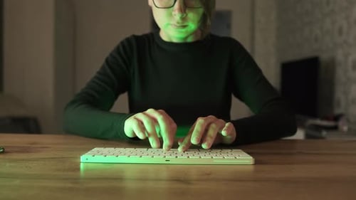 Jeune femme travaille, étudie à domicile en utilisant un ordinateur la nuit au feu vert, communique en ligne