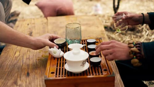 close-up The hands of a professional tea master who pours fresh natural green tea from a glass