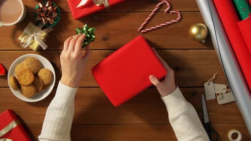 Wrapping Christmas Present with Bow on Wooden Table