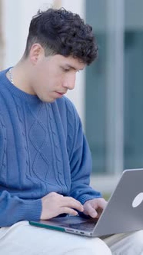 Young Adult Working on Laptop in Urban Setting