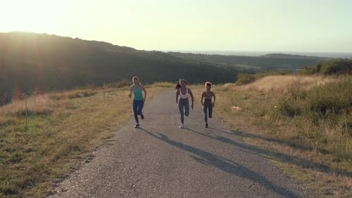 Women Jogging on Rural Road During Sunrise