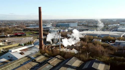 Pilkington glass factory warehouse buildings aerial view zoom in towards smoking industrial facility
